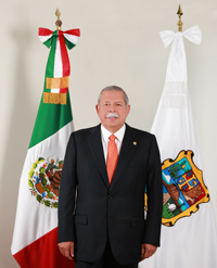 photo of Egidio Torre-Cantu standing in front of flags