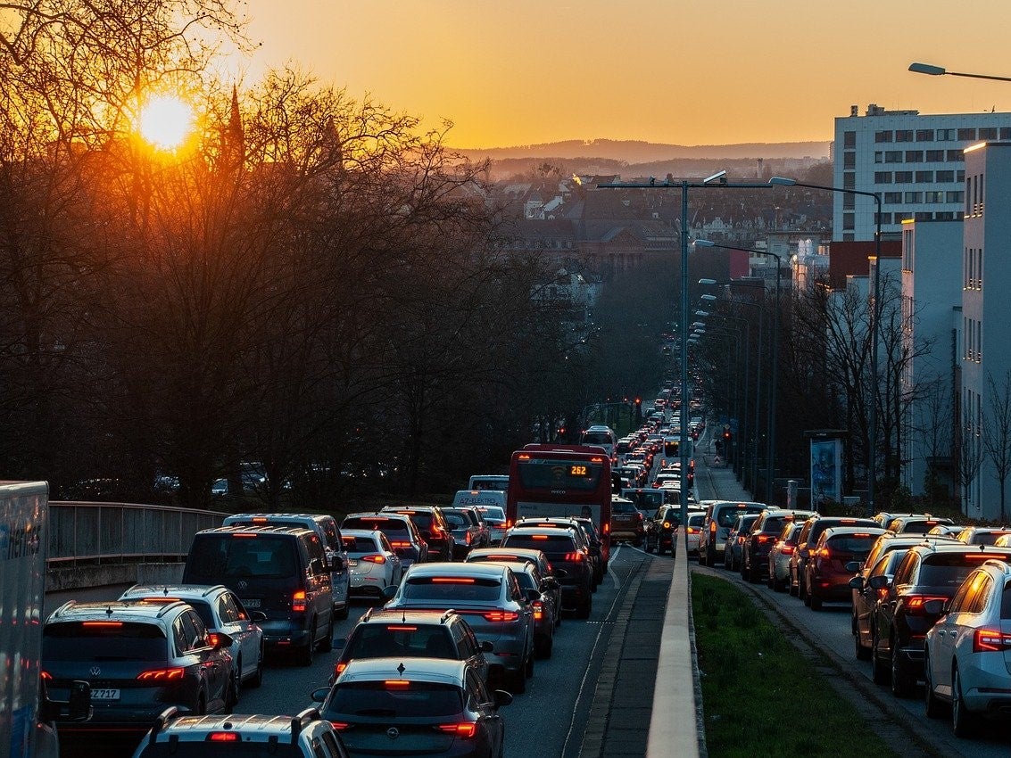 Cars sitting in traffic in a city at sunset