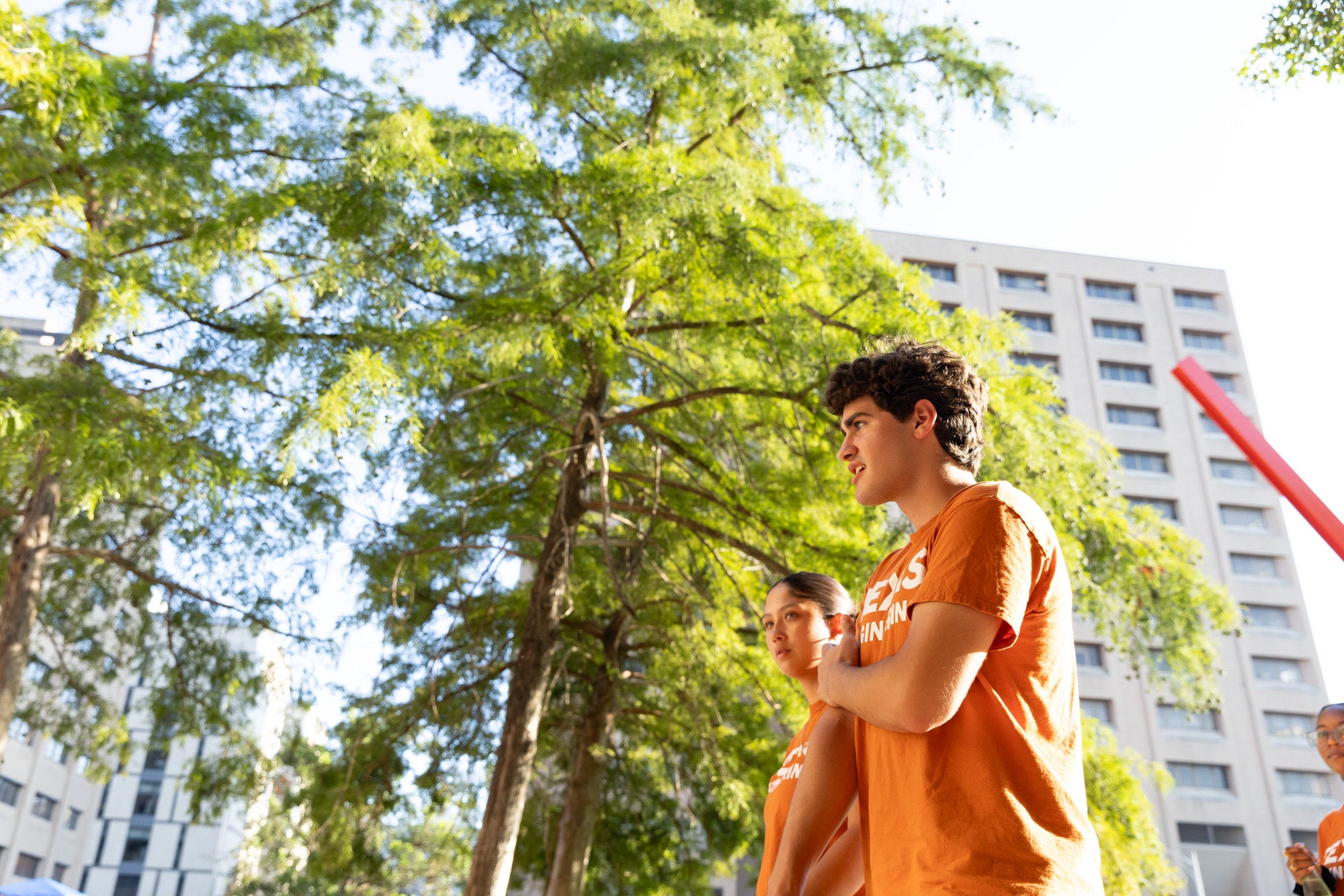 Texas Engineering students walking across campus with green trees in background