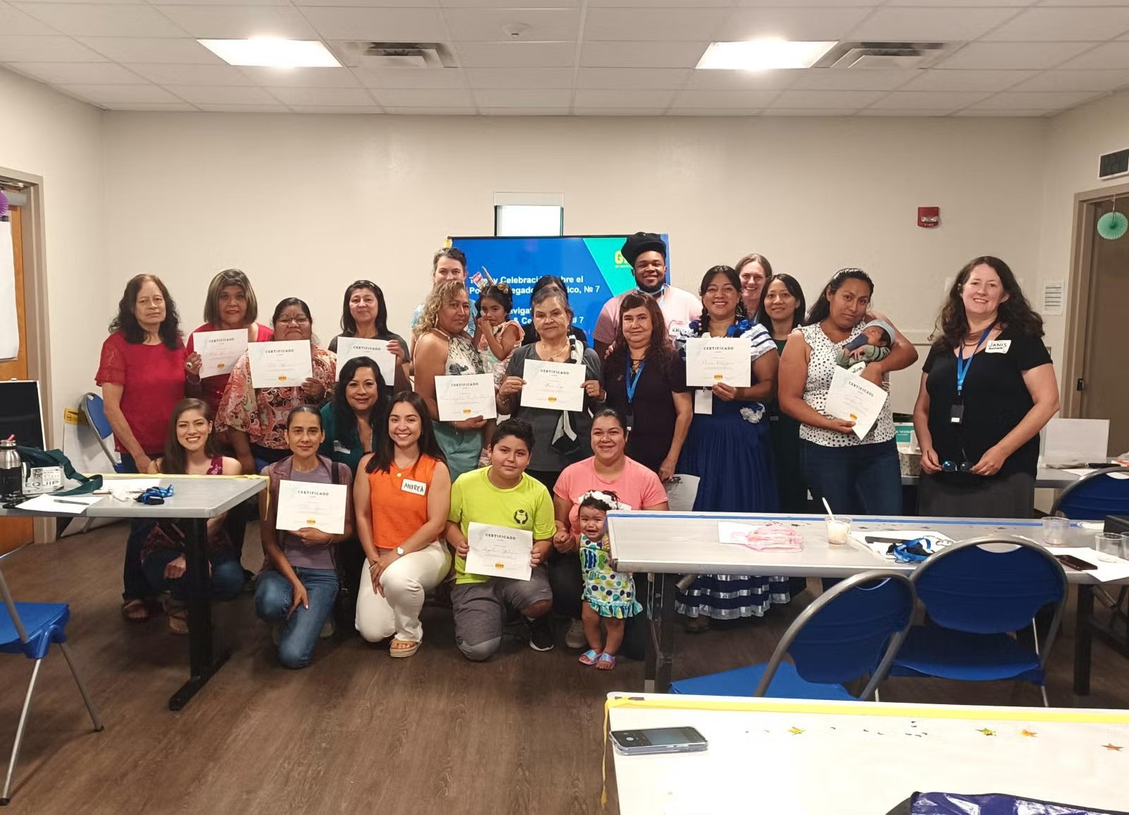 The Climate Navigators group and other project leaders smiling in empty classroom holding certificates