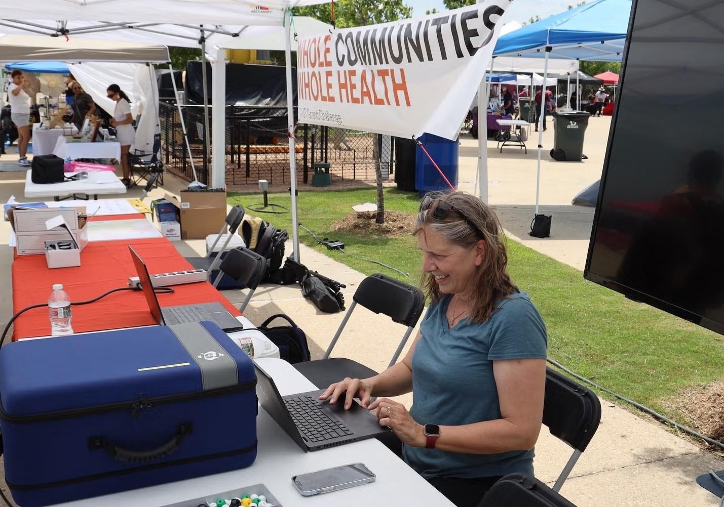 Texas CAEE professor Kerry Kinney sitting at booth during Whole Communities Whole Health event