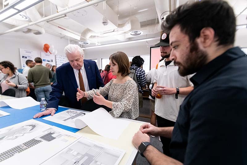 Texas Engineer Thomas Taylor looking at table of papers surrounded by students